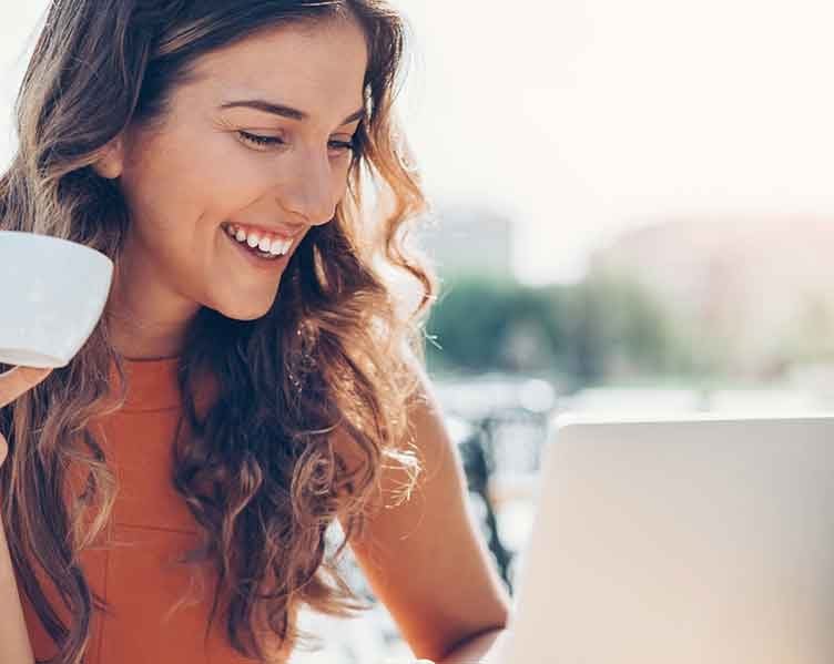 Frau mit Kaffeetasse und Laptop
